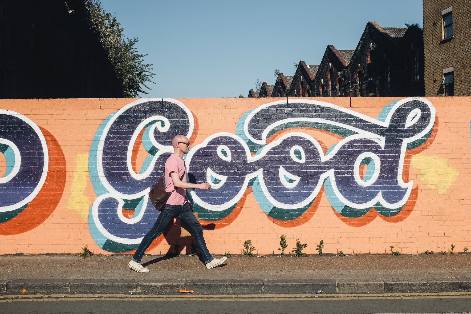 Bald man walks in front of graffiti